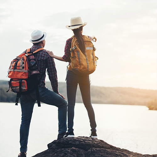 Man and woman standing on mountain watching sunrise | Book Now Pay Later | Travel on EMI | Mihuru